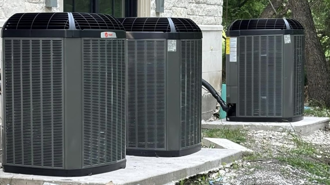 Three newly installed Trane air conditioning condenser units at a residential home